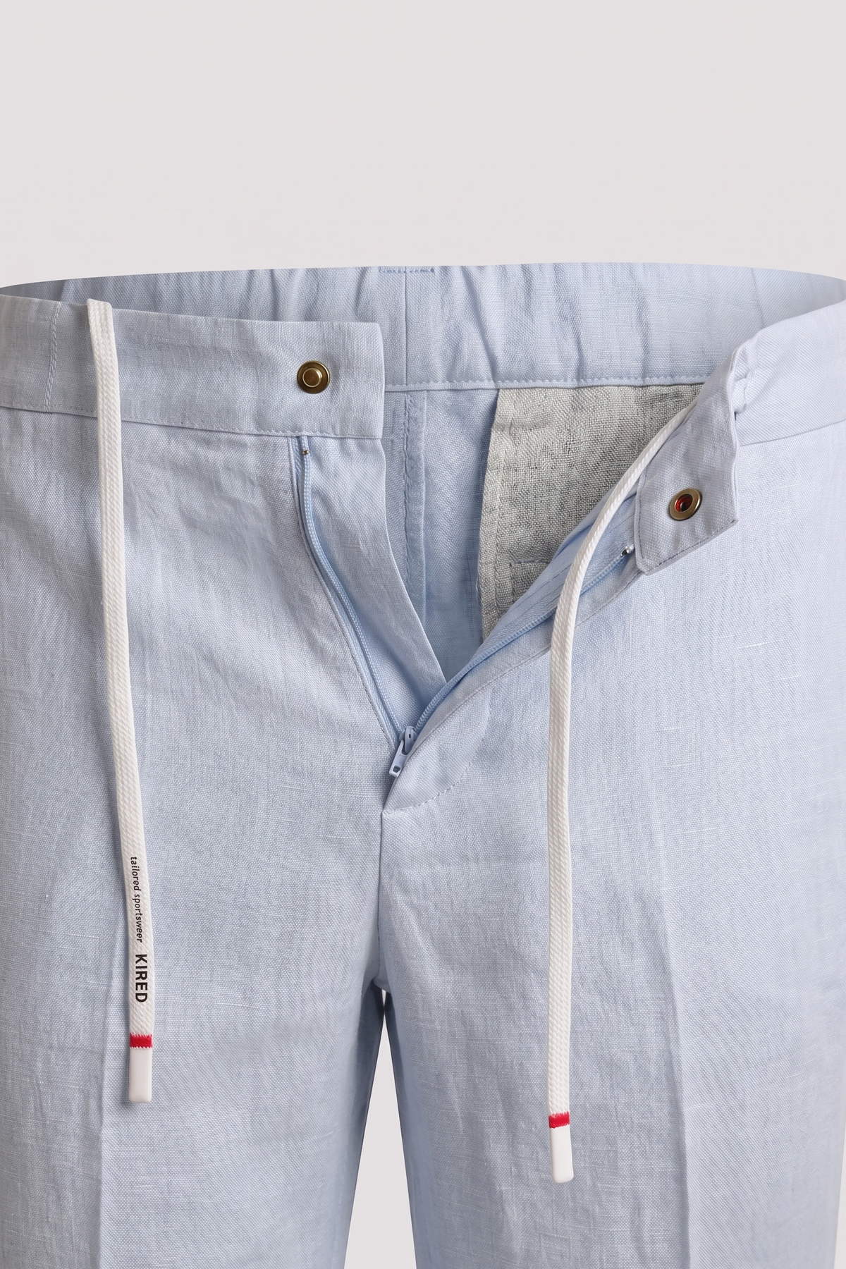 Light blue pants with a close-up of the waistband and side seam on a light gray background.